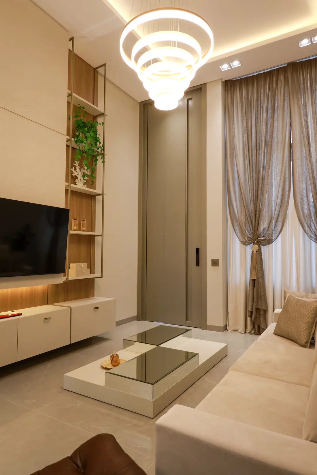 Sala de estar projetada pelo Studio 34, com painel de TV, estante e iluminação decorativa